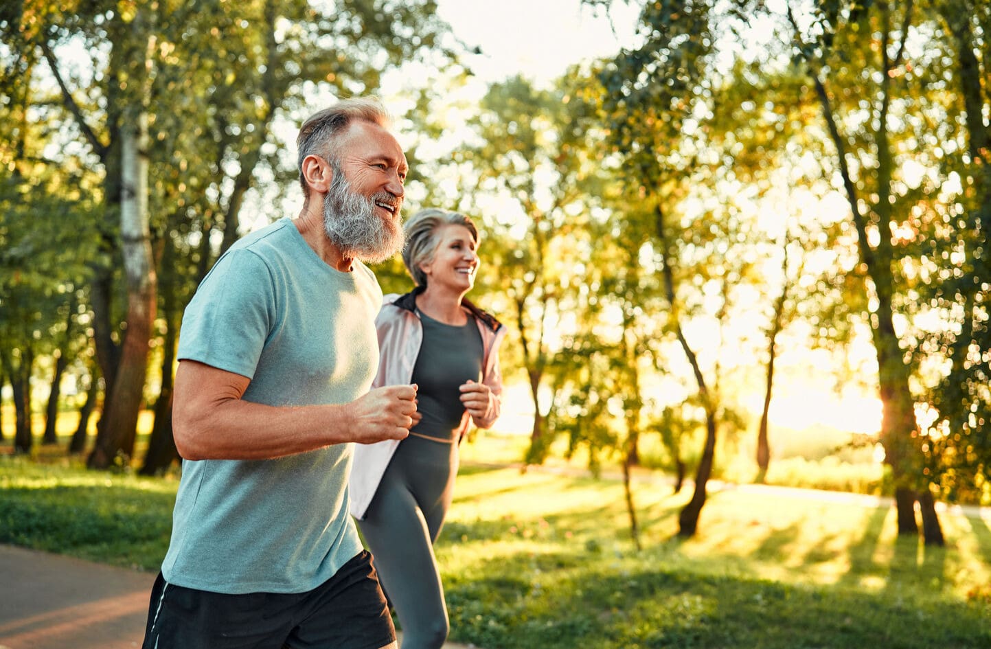 Couple jogging in a park on a sunny day.